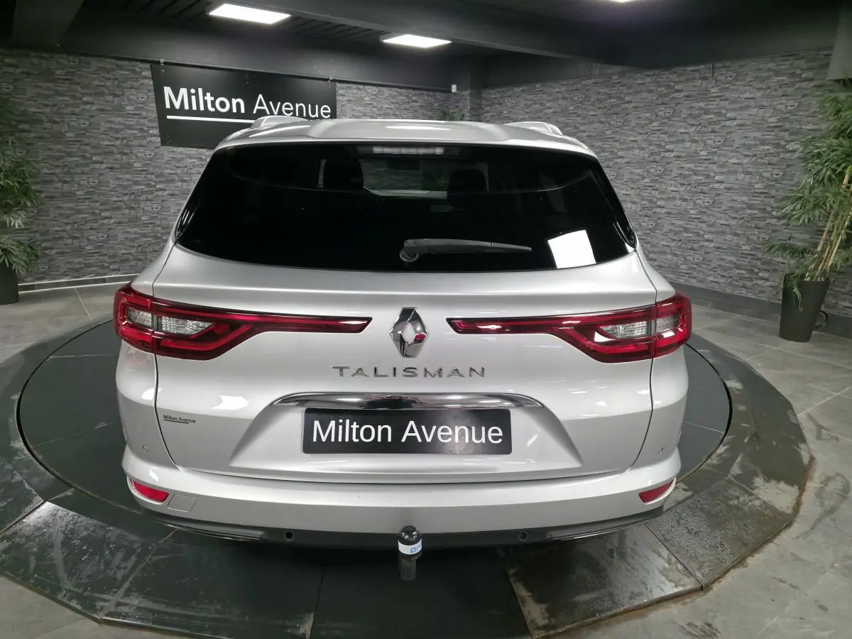 Vue arrière d'un break Renault Talisman gris avec hayon motorisé et attelage démontable, en showroom.