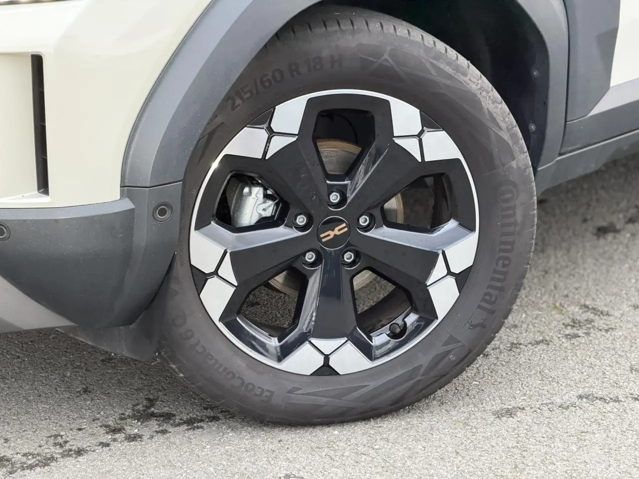 Gros plan sur la roue avant droite du Dacia Duster Beige Sandstone avec jante alliage noire et argentée.