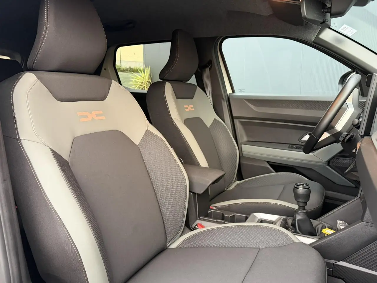 Vue intérieure côté droit montrant les sièges TEP MicroCloud beige et brun cuivré du Dacia Duster 2025 avec levier de vitesses manuel.