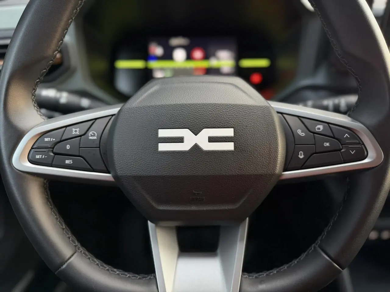 Gros plan sur le volant noir du Dacia Duster 2025 avec commandes intégrées et logo Extrême au centre.