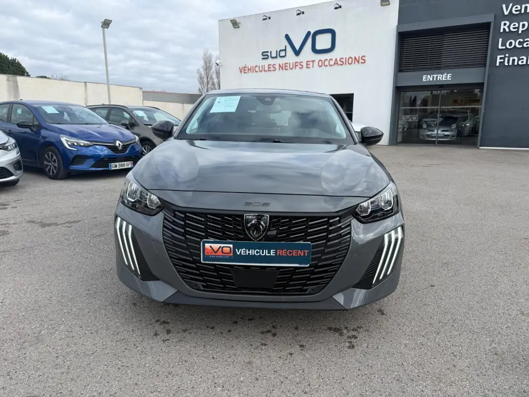 Vue avant d'une Peugeot 208 Hybrid 145 gris, avec calandre noire et feux diurnes LED en griffes distinctives.
