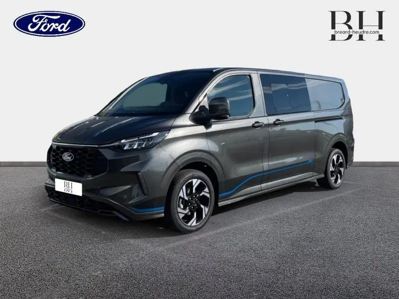 Ford Transit Custom Fourgon gris Magnetic métallisé, vue 3/4 avant droit avec jantes alu et vitres latérales surteintées.
