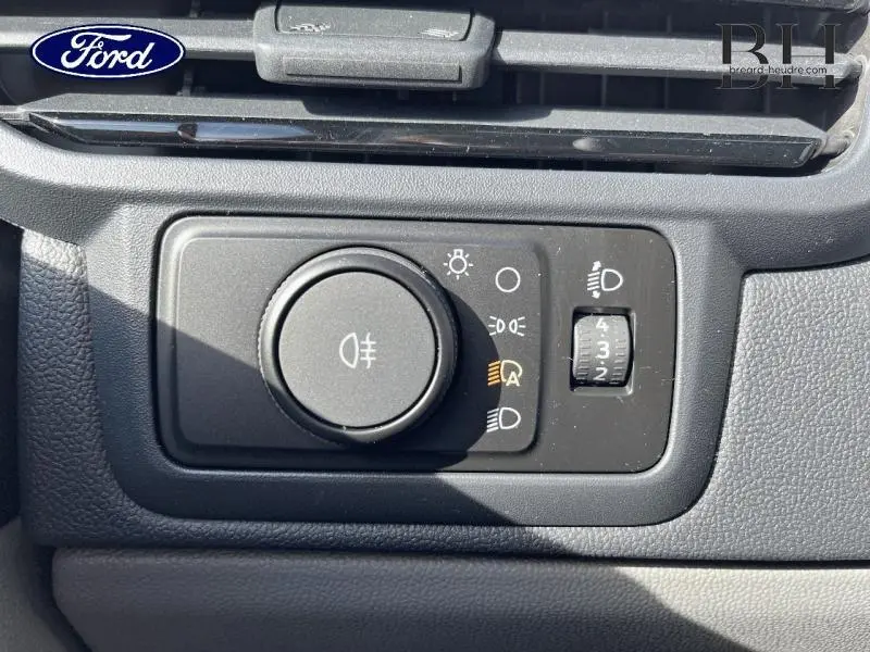 Gros plan sur le bouton de commande des phares dans l’habitacle gris du Ford Transit Custom Fourgon 2026.