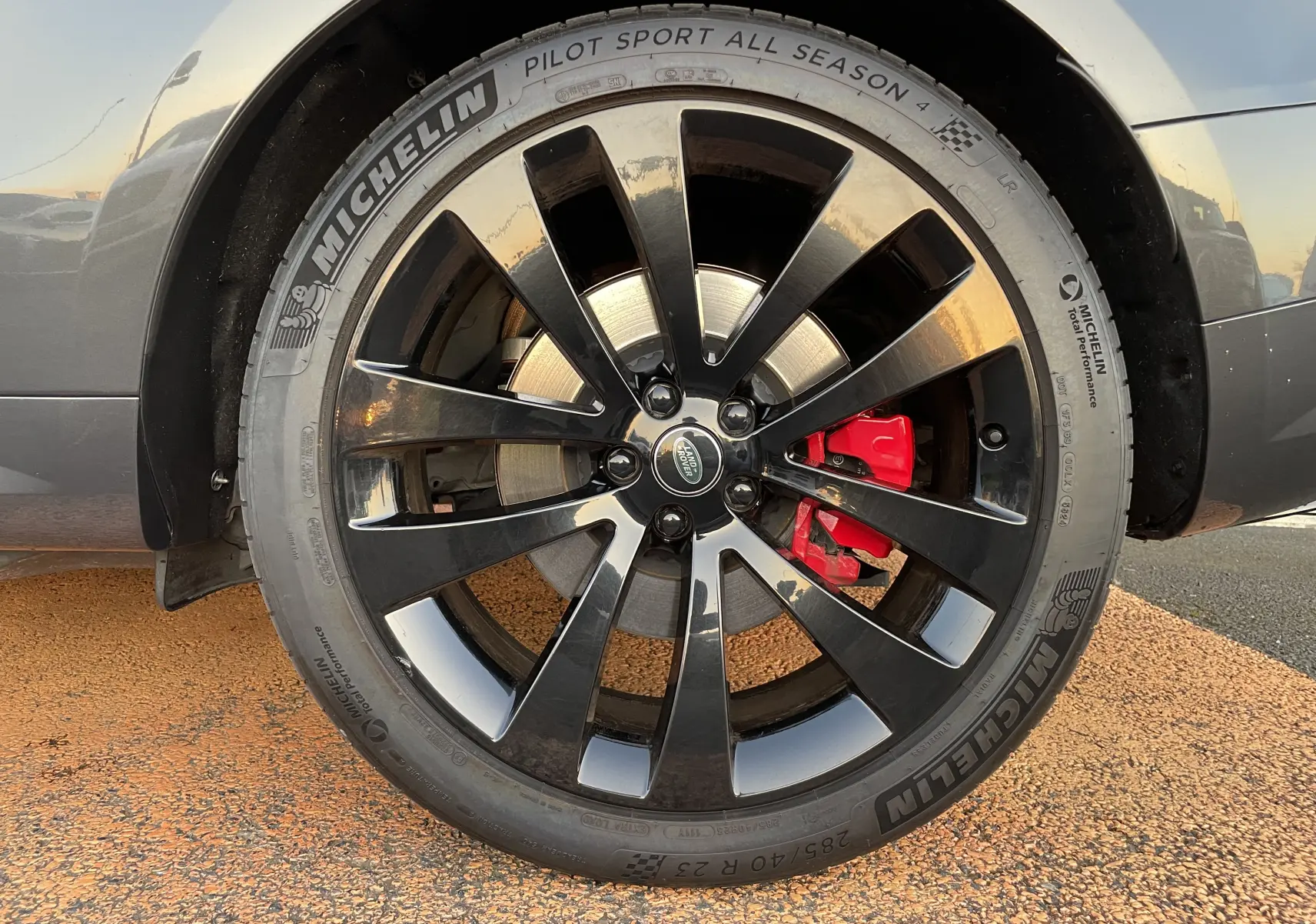 Gros plan sur la jante noire brillante 23'' avec étrier de frein rouge du Range Rover Sport Carpathian Grey 2023.