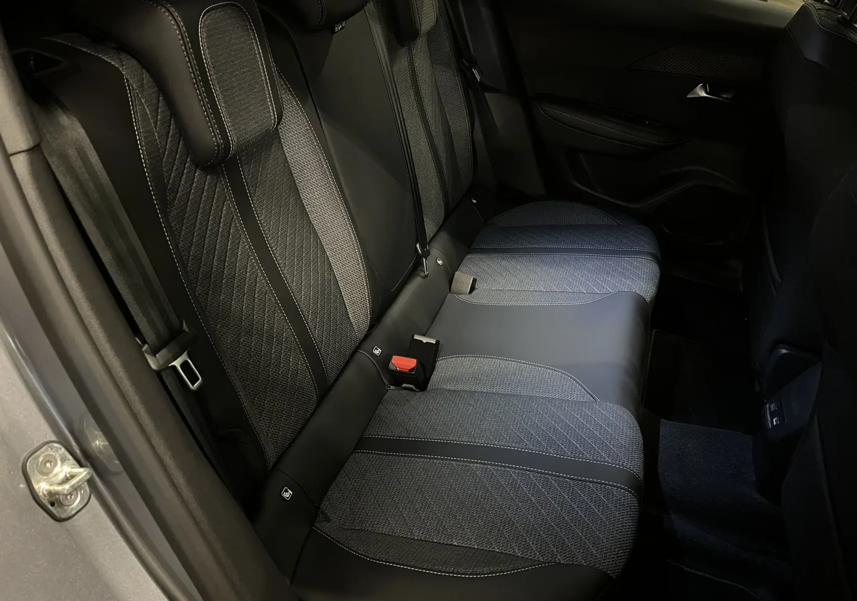 Vue intérieure côté arrière droit du Peugeot 2008 1.2 Hybrid 145ch, sièges en tissu et cuir noir avec surpiqûres blanches.