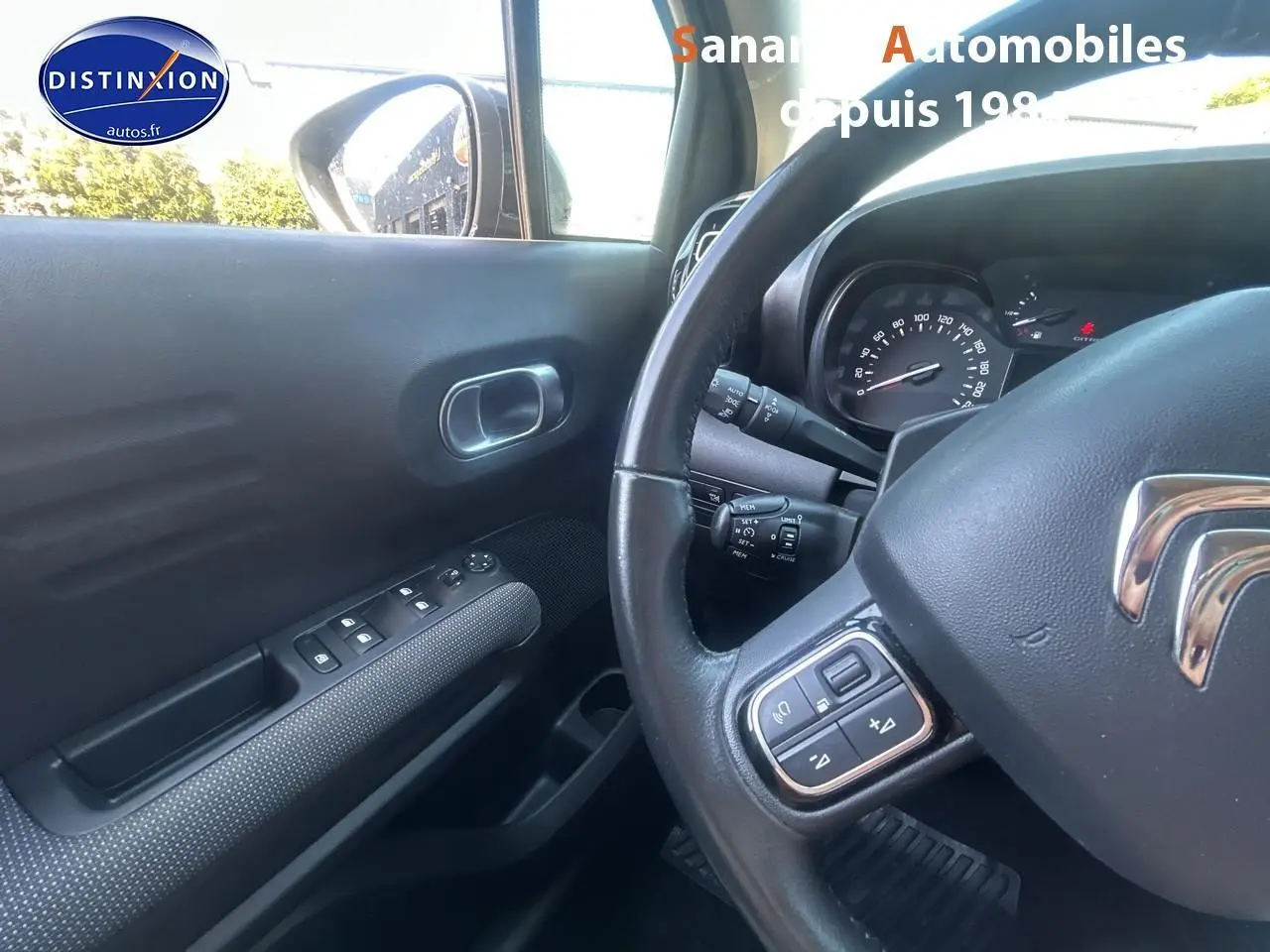 Vue intérieure côté conducteur du Citroën C3 Aircross gris foncé, avec volant multifonction et commandes sur portière.