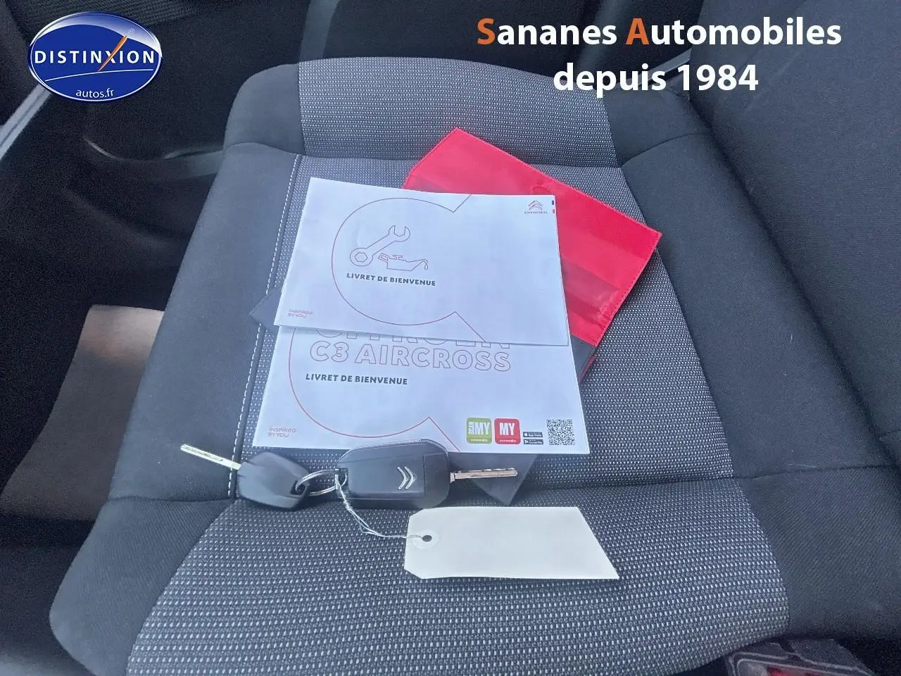 Clé et livret de bienvenue Citroën C3 Aircross posés sur un siège tissu gris à l'intérieur du véhicule.