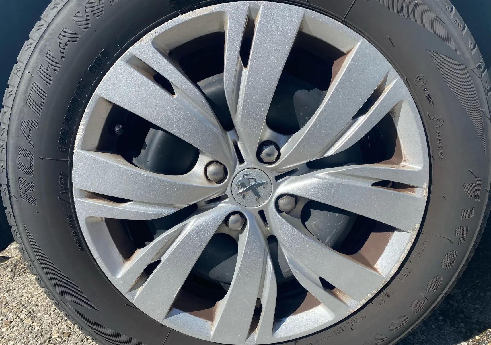 Gros plan sur la jante argentée d'une Peugeot 208 blanche, modèle 1.0 PureTech Active 2014, avec pneu Firestone.