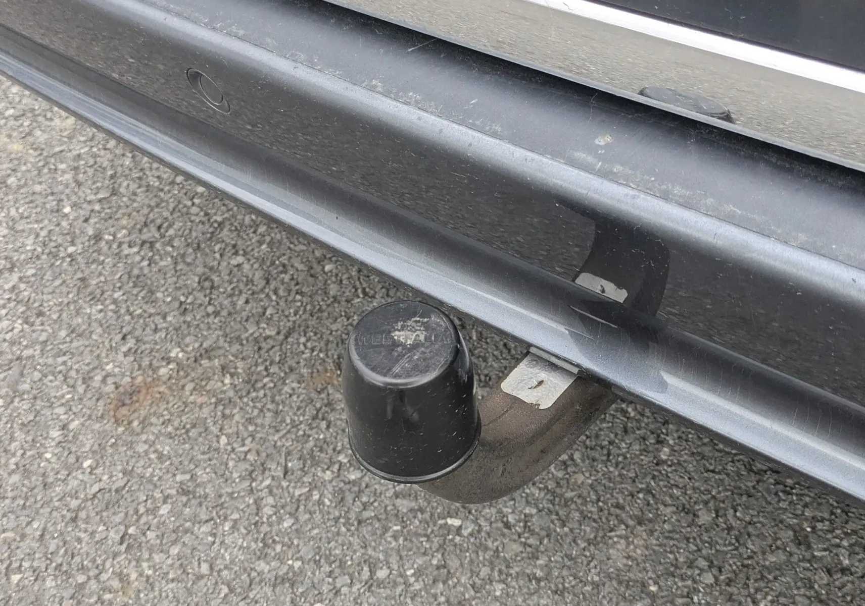 Gros plan sur l'attelage de remorque noir sous le pare-chocs arrière gris du Mercedes Viano 3.0 CDI.