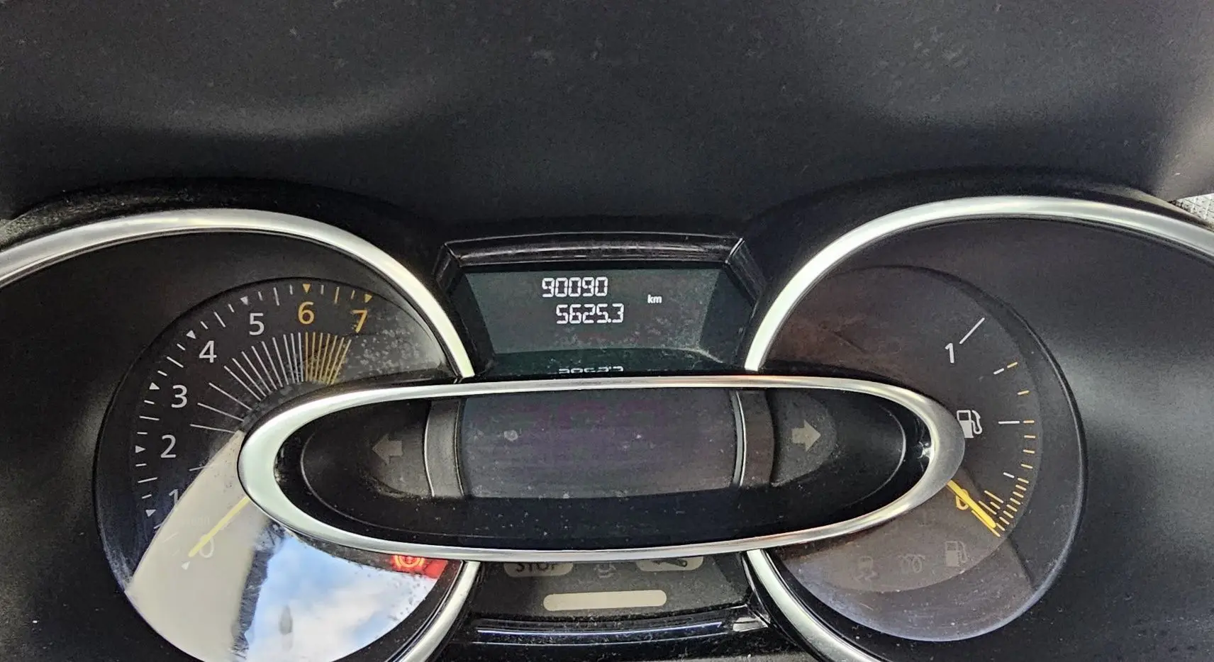 Gros plan sur le tableau de bord de la Renault Clio IV grise, affichant le compteur kilométrique et le niveau de carburant.