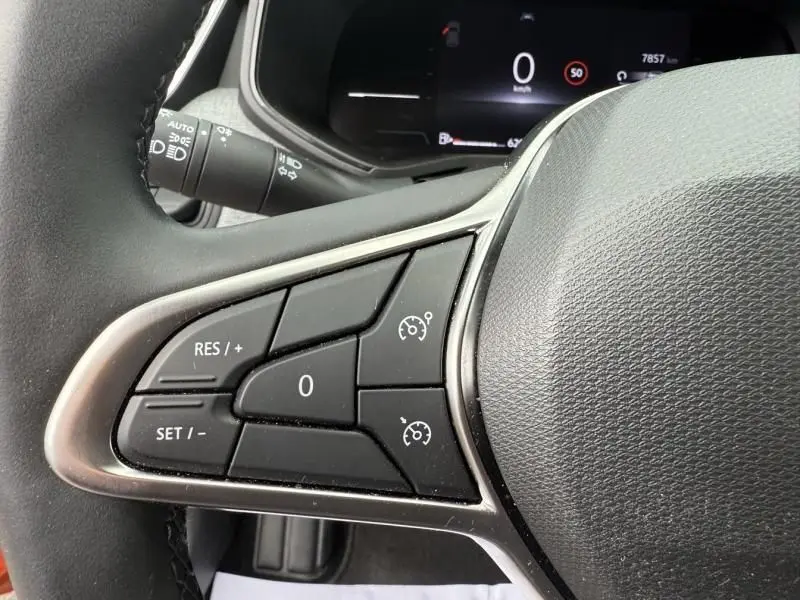 Gros plan sur les commandes de régulateur de vitesse au volant d'une Renault Clio V orange essence 2025.