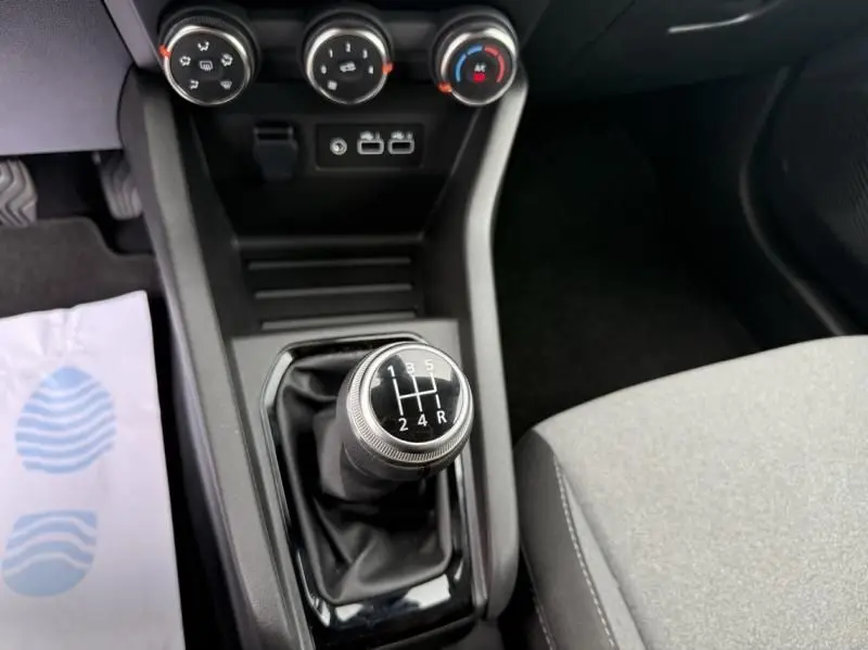 Gros plan sur le levier de vitesses manuel de la Renault Clio V SCE 65 Evolution 2025, intérieur sobre et commandes de climatisation.