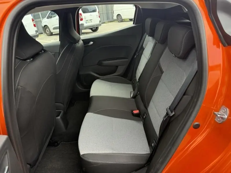 Intérieur arrière de la Renault Clio V orange 2025, vue côté gauche montrant les sièges bicolores gris et noir.