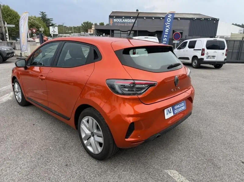 Vue 3/4 arrière droite d'une Renault Clio V orange 2025 SCE 65 Evolution essence avec jantes alliage, stationnée en extérieur.