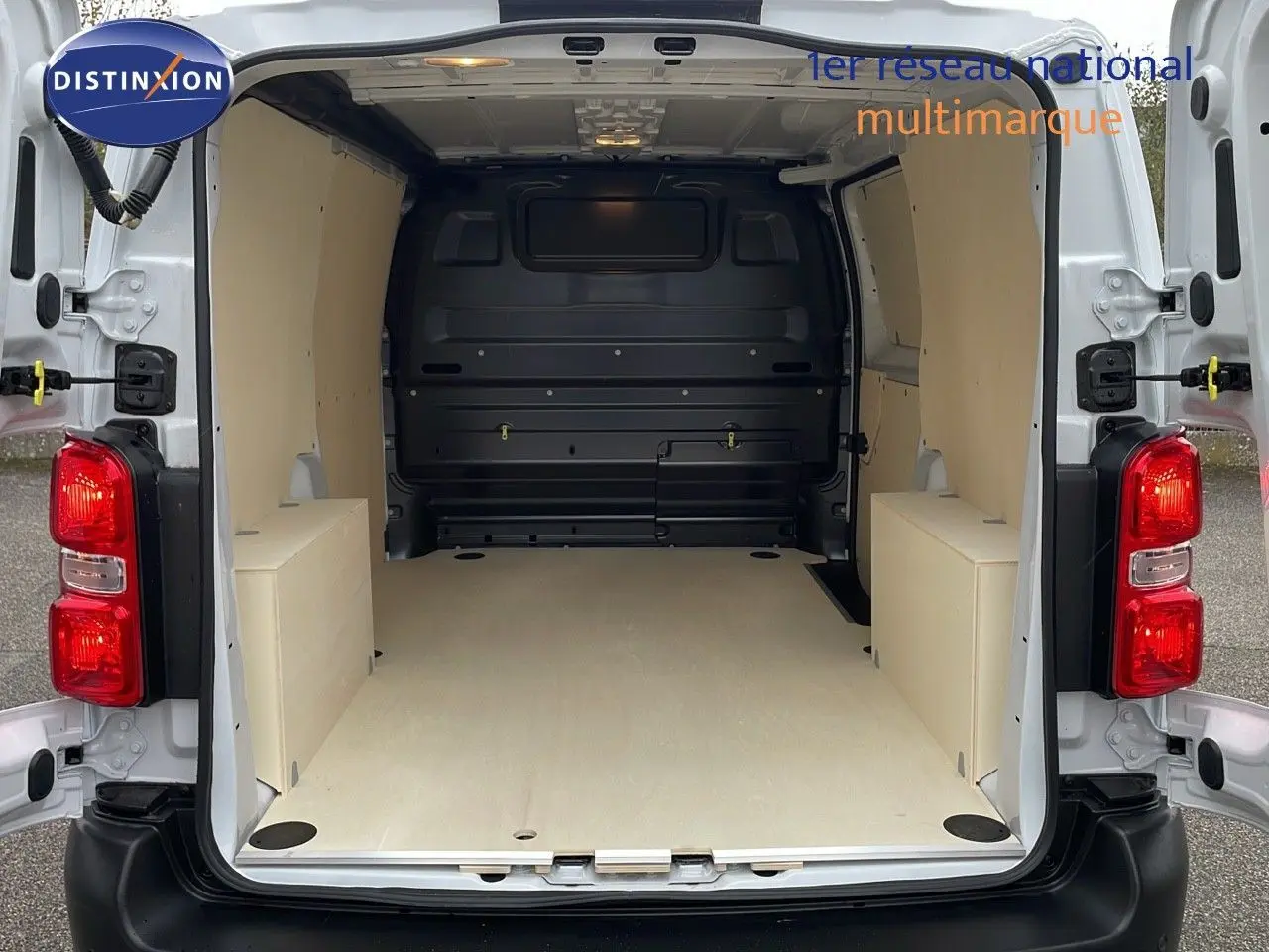 Vue arrière du Peugeot Expert Fourgon blanc icy 2025 avec portes ouvertes montrant l'espace de chargement aménagé en bois clair.