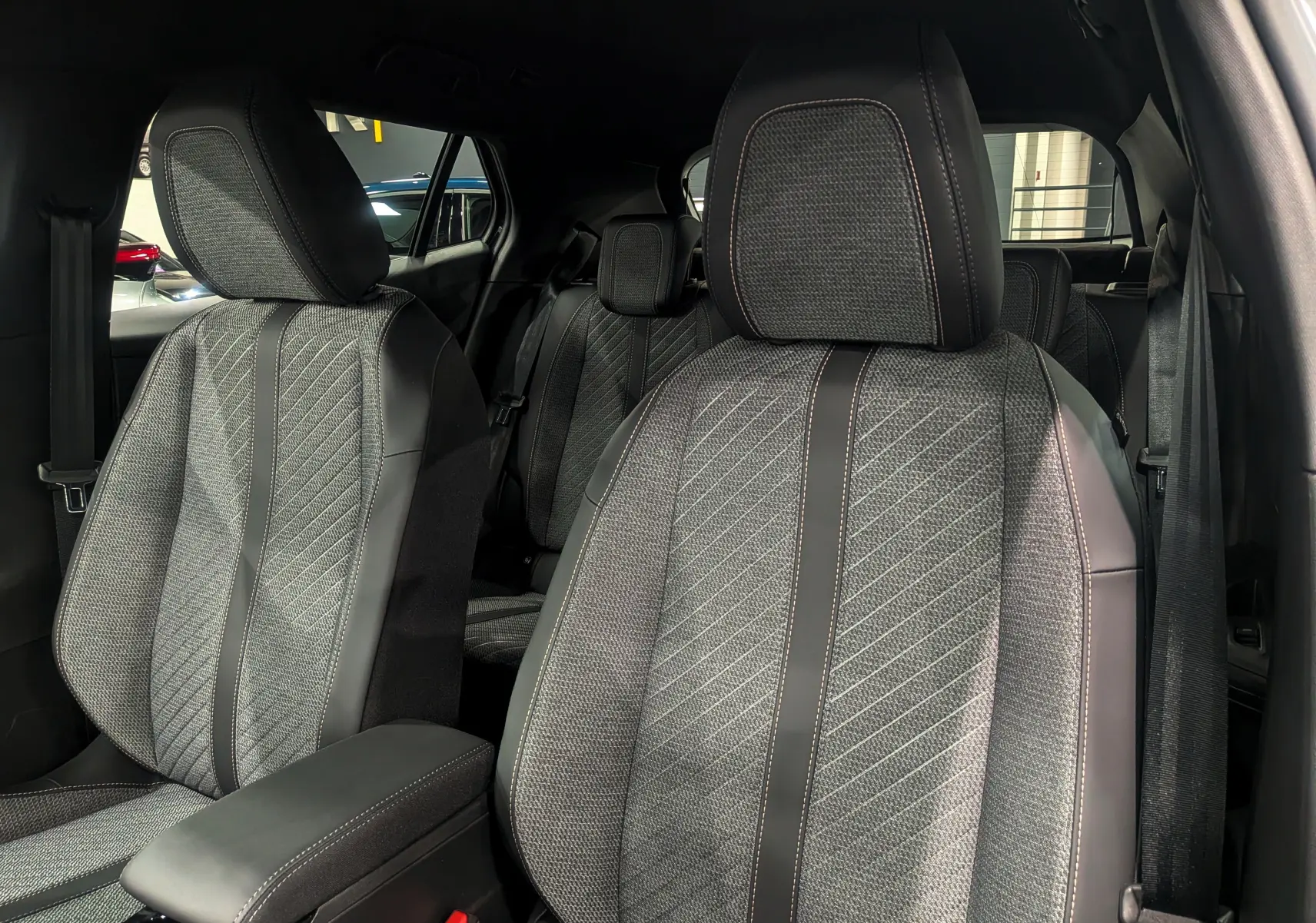 Gros plan sur les sièges avant en tissu gris et cuir noir du Peugeot 2008 Hybrid 145 e-DCS6 Allure 2025.
