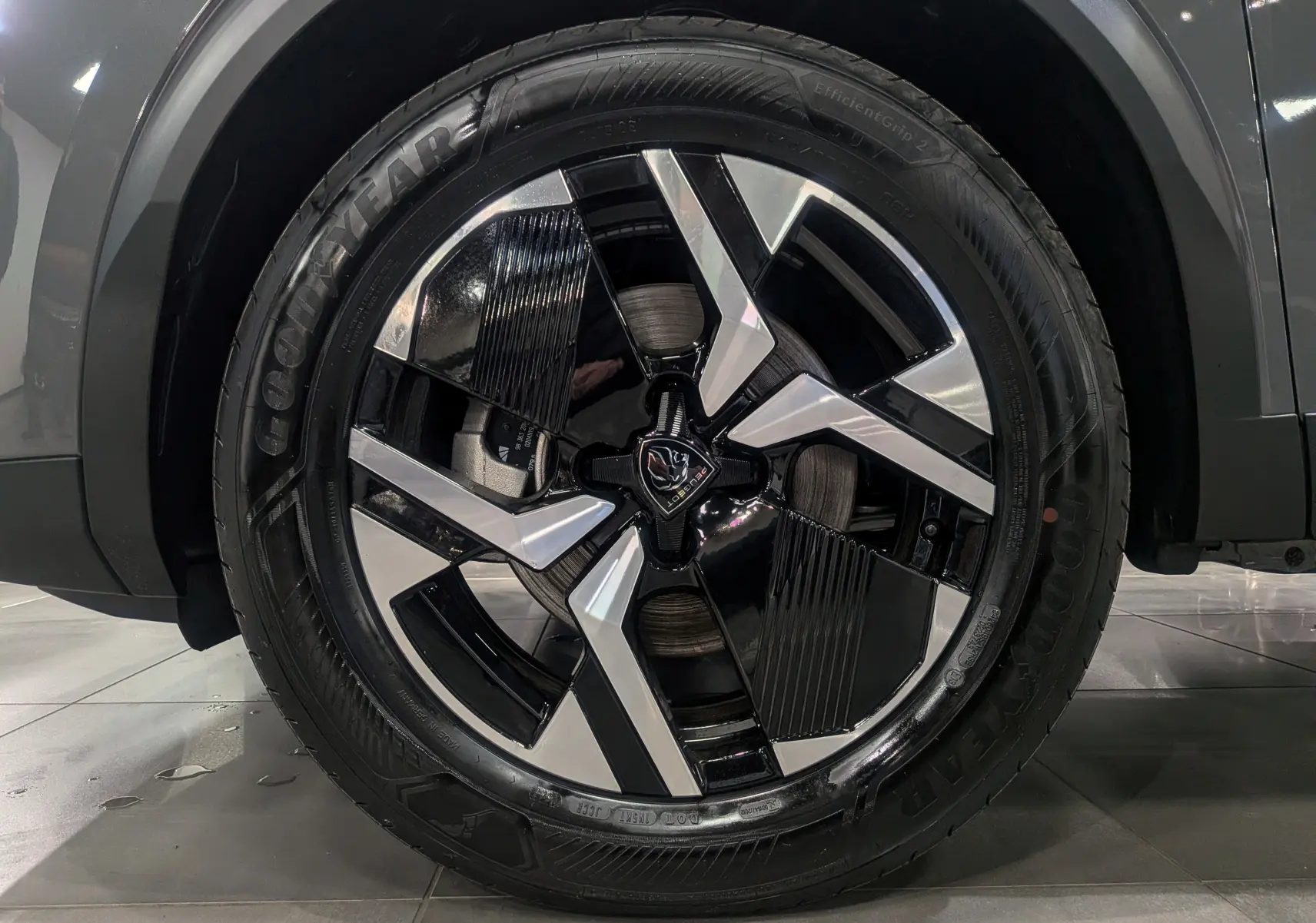 Gros plan sur la jante avant droite bicolore noir et argent du Peugeot 2008 Hybrid 145 e-DCS6 gris Sélénium 2025.