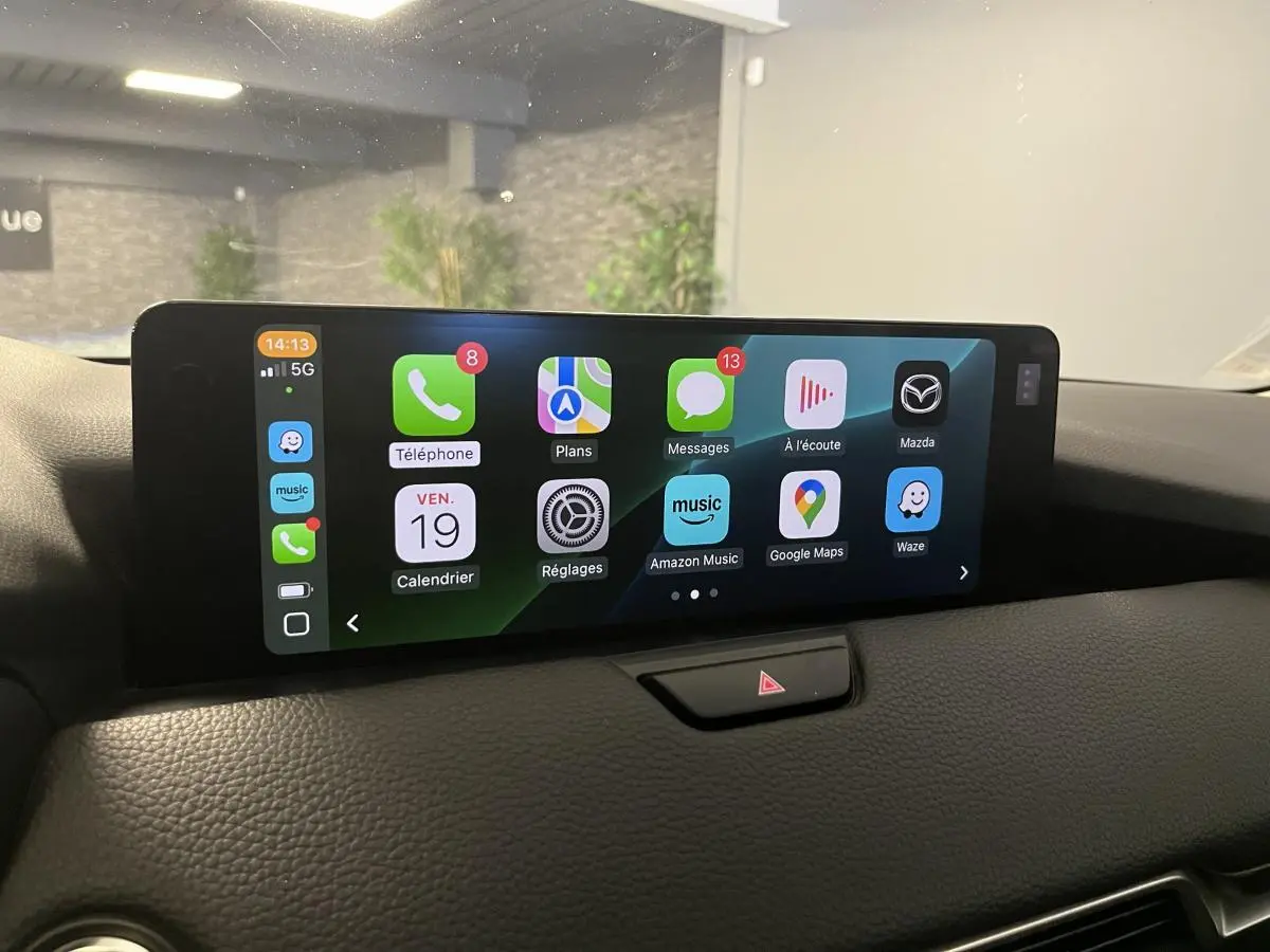 Écran central tactile du Mazda CX-60 2023 affichant Apple CarPlay avec plusieurs applications visibles.
