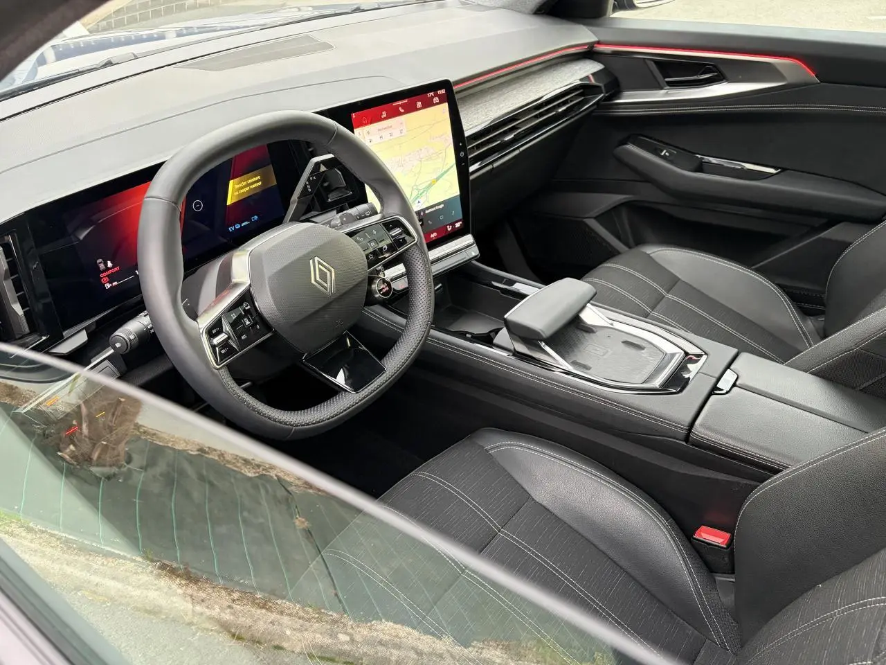 Vue intérieure côté conducteur du Renault Austral 2025, avec volant compact, écran tactile vertical et sellerie mixte noire.