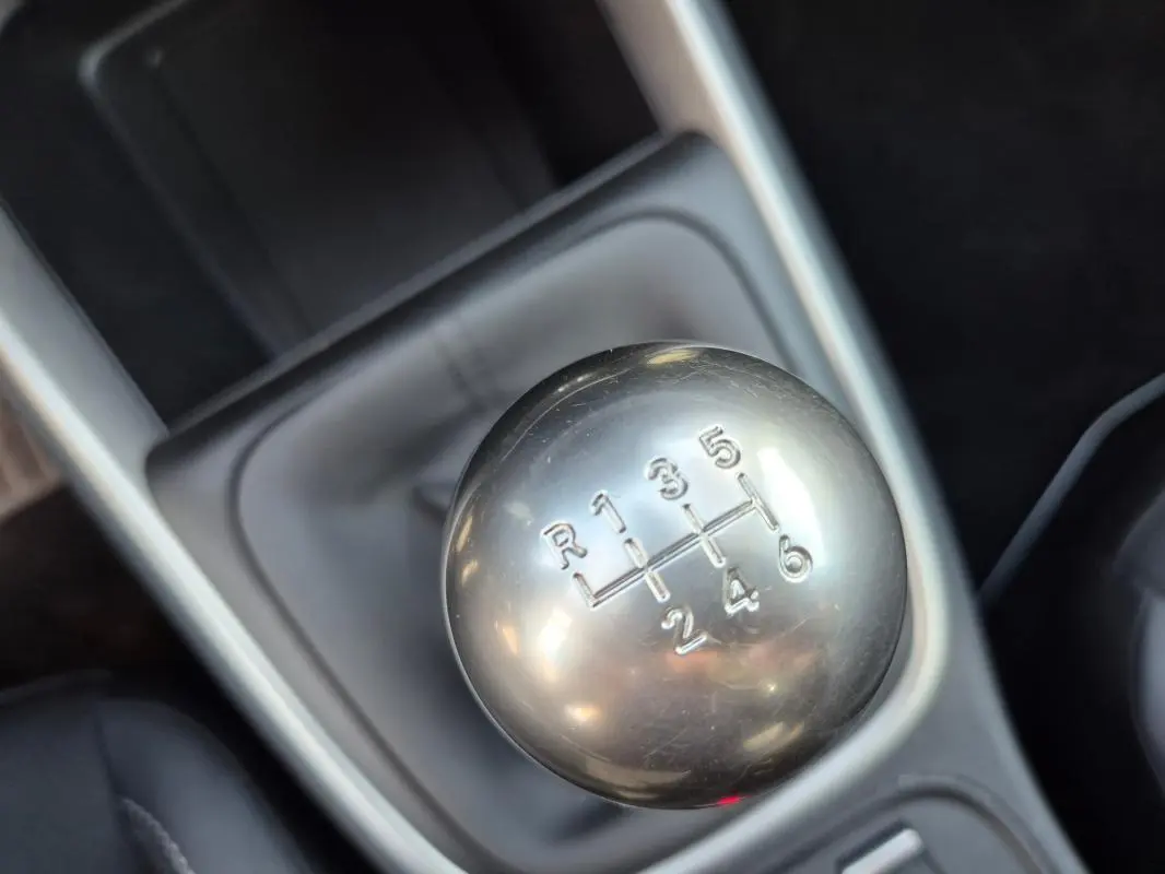 Gros plan sur le levier de vitesses manuel argenté du Jeep Avenger noir, version 2024, avec console grise en arrière-plan.