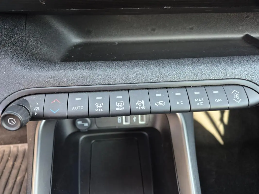 Gros plan sur la rangée de boutons de commande de la climatisation et volume dans l’habitacle noir du Jeep Avenger 2024.