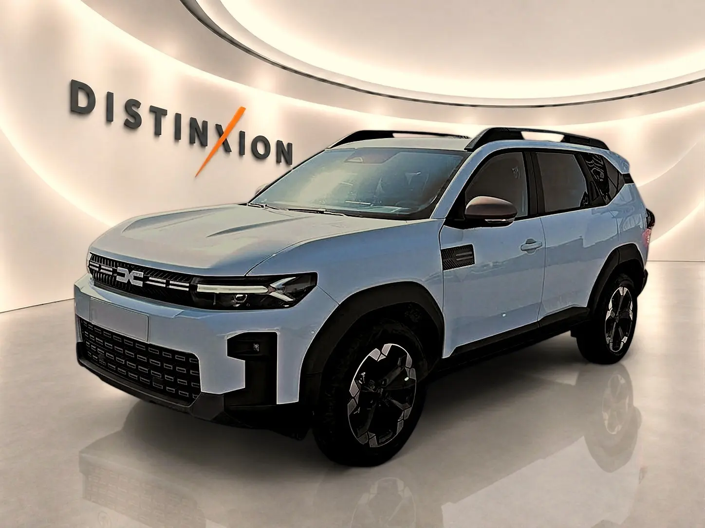 Dacia Bigster blanc en 3/4 avant droit, avec barres de toit noires et jantes alu distinctives.