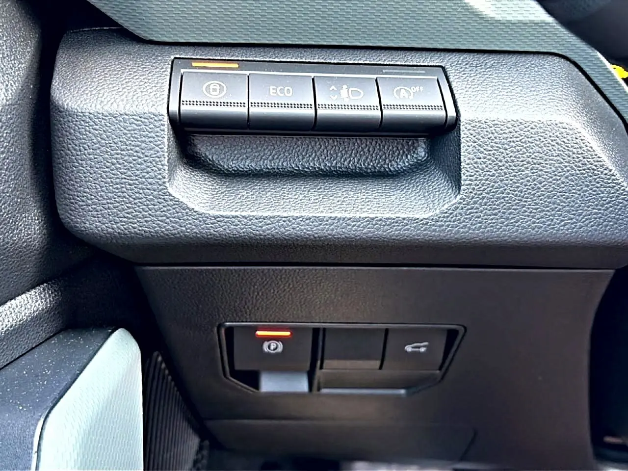 Gros plan sur les commandes noires du tableau de bord du Dacia Bigster, avec bouton Eco et frein à main électronique.