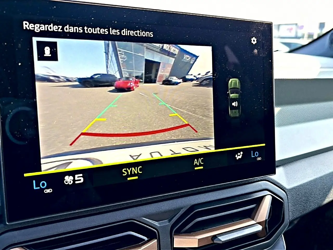 Écran tactile intérieur du Dacia Bigster blanc montrant la caméra de recul avec guidage de trajectoire coloré.