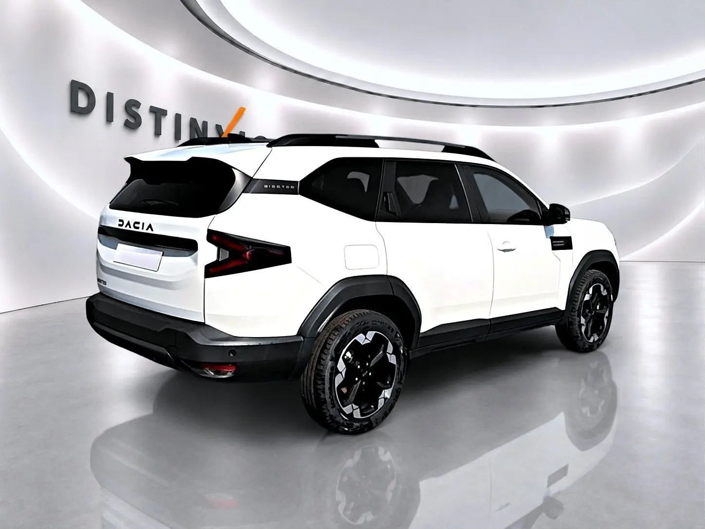 Vue 3/4 arrière droite du Dacia Bigster blanc avec jantes noires et toit noir dans un showroom lumineux.