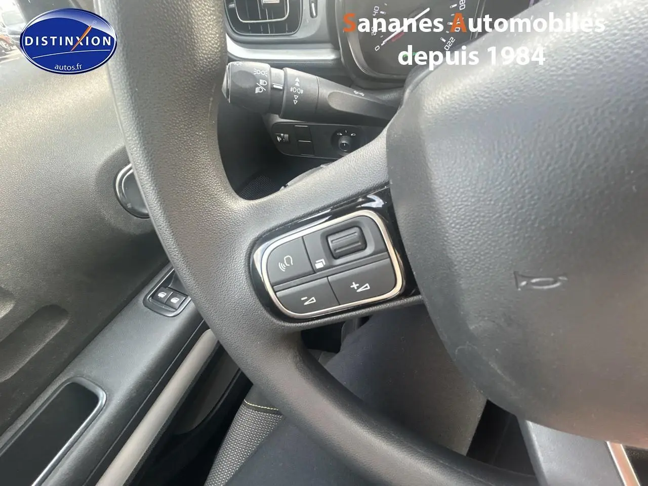 Gros plan sur les commandes audio au volant d'une Citroën C3 2023, intérieur gris foncé.