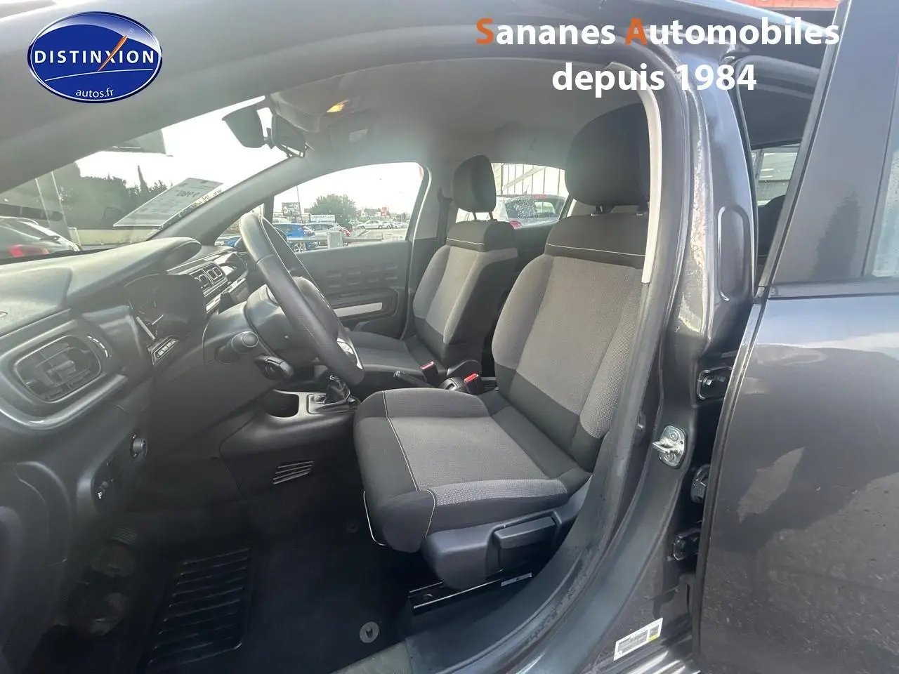 Intérieur côté conducteur d'une Citroën C3 gris foncé 2023, montrant les sièges tissu Mica Grey et la boîte manuelle.