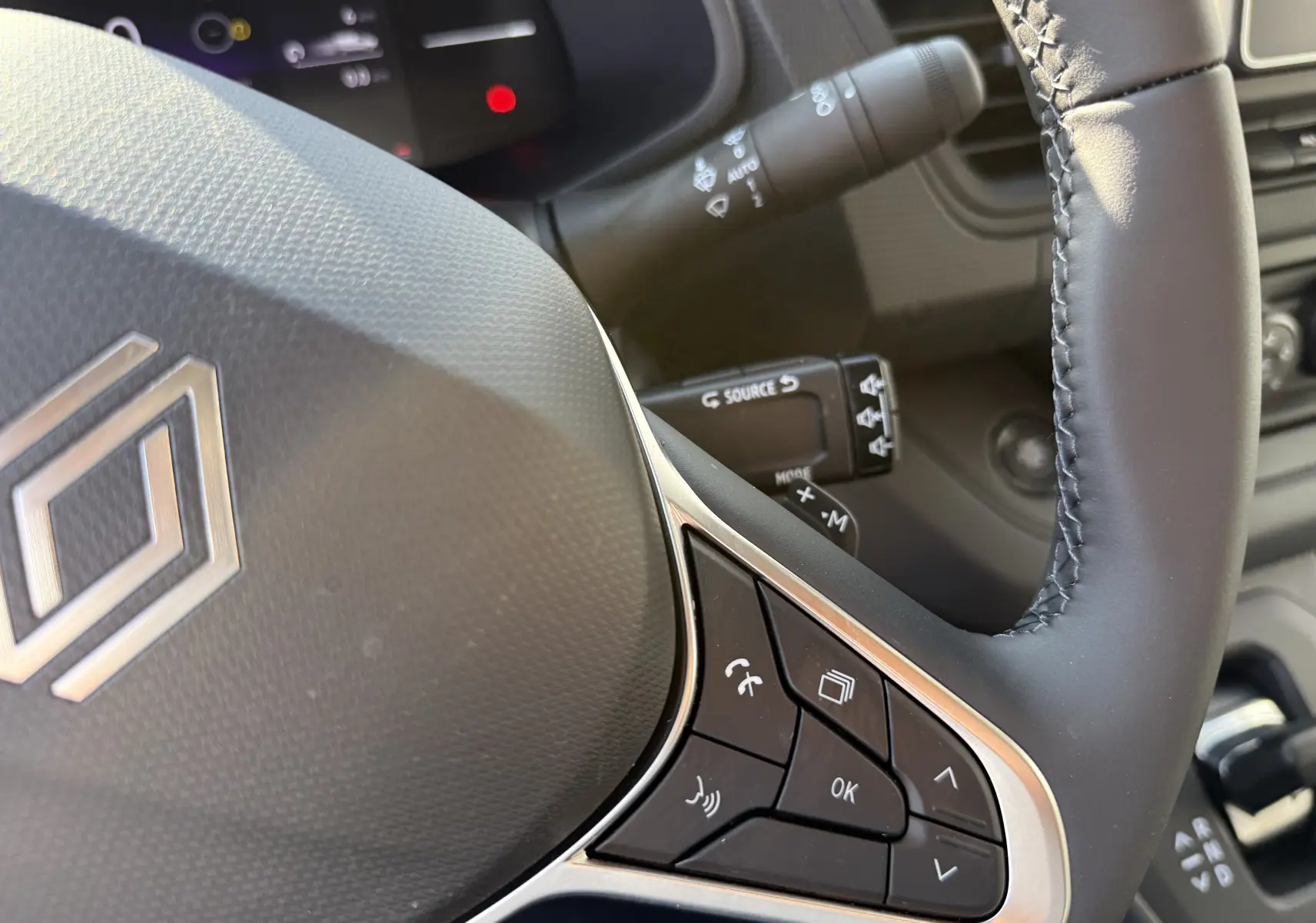 Gros plan sur le volant noir du Renault Trafic 2025 avec commandes intégrées et détails du tableau de bord en arrière-plan.
