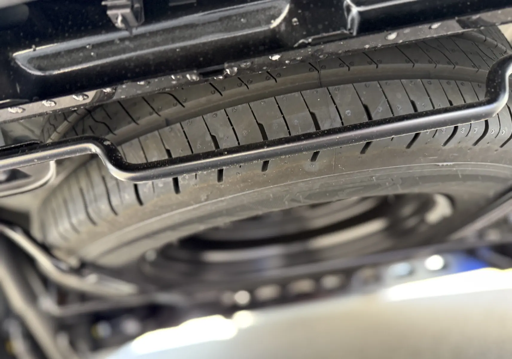 Gros plan sur la roue de secours sous le châssis du Renault Trafic Cabine Approfondie noir, vue en contre-plongée.