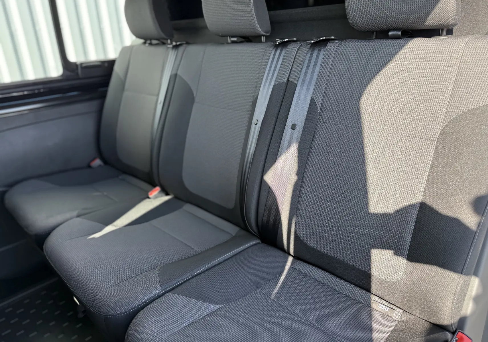 Vue intérieure rapprochée des sièges arrière en tissu gris foncé du Renault Trafic Cabine Approfondie L2H1 2025.