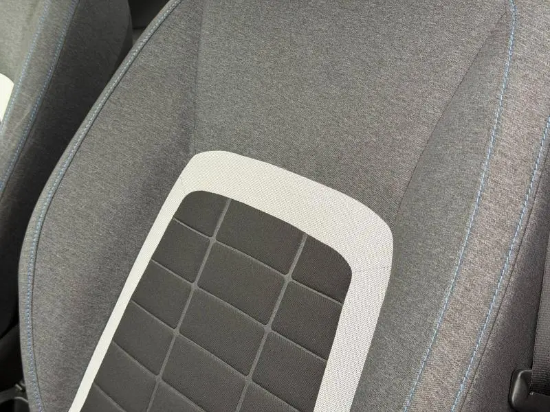 Gros plan sur le siège avant de la Citroën C3 2025, tissu gris avec motif quadrillé noir et surpiqûres bleues.