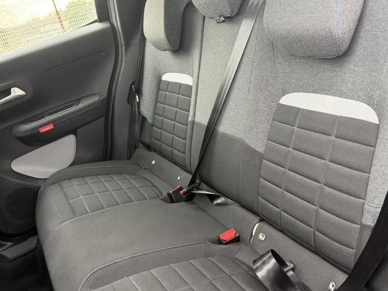 Vue intérieure du siège arrière côté gauche de la Citroën C3 2025 avec sellerie tissu gris et noir à motifs carrés.