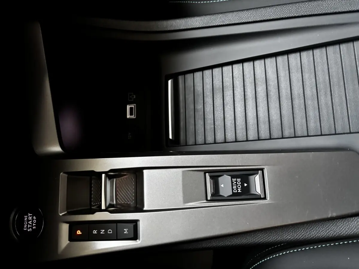 Vue rapprochée de la console centrale de la Peugeot 308 Hybrid 136 e-DCS6 Allure 2025, avec commandes boîte auto et bouton Drive Mode.