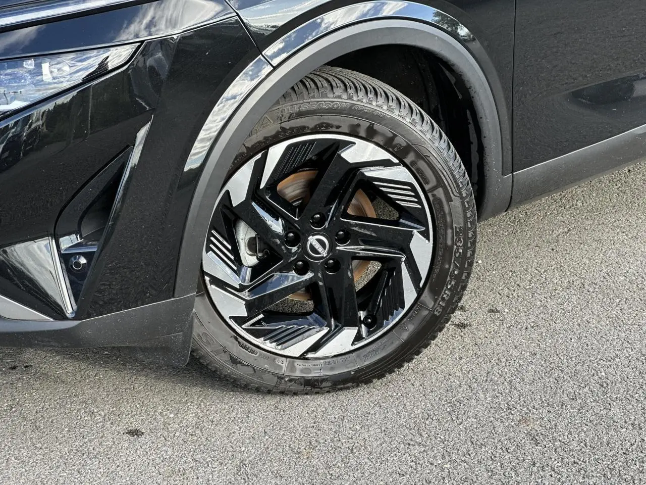 Gros plan sur la roue avant gauche du Nissan Qashqai noir nacré avec jante alliage 18 pouces au design moderne.