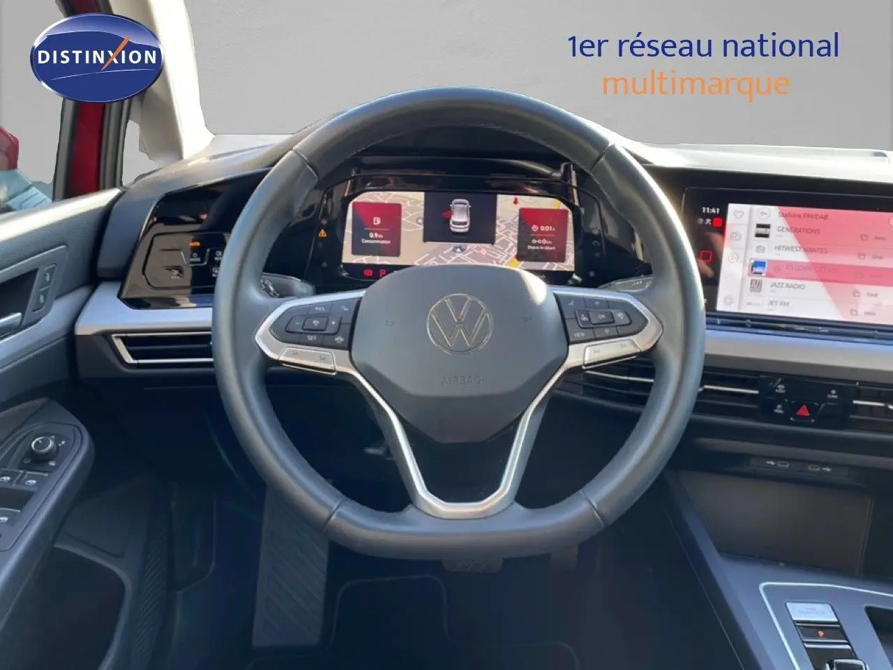 Vue intérieure centrée sur le volant et tableau de bord numérique d’une Volkswagen Golf VIII rouge Roi Metal de 2023.