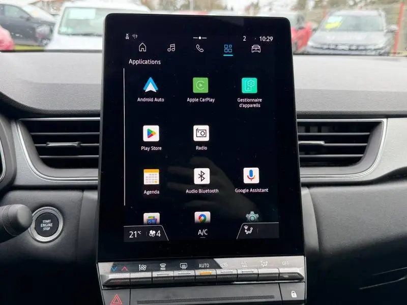 Vue intérieure centrée sur l'écran tactile du tableau de bord du Renault Captur 2025, avec commandes climatisation visibles.
