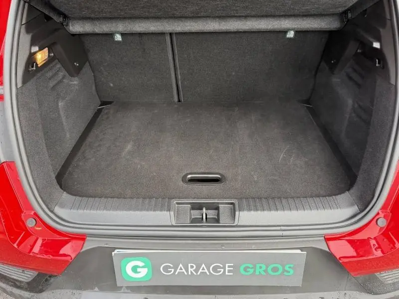 Coffre ouvert vu de l'arrière d'un Renault Captur 2025 Rouge Flamme, montrant l'espace de chargement vide.