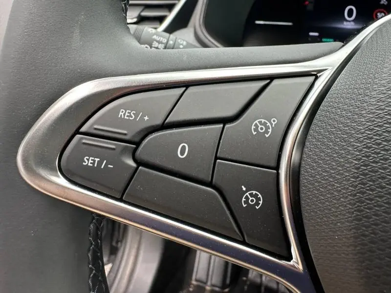 Gros plan sur les commandes de régulateur de vitesse au volant noir de la Renault Clio Gris Rafale 2025.