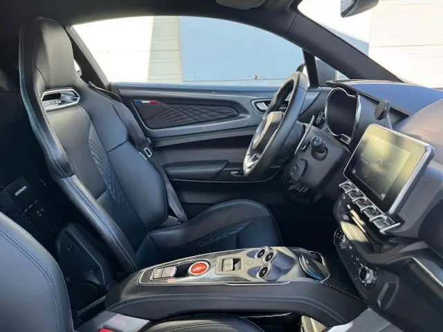 Intérieur côté conducteur de l'Alpine A110 1.8T 252 Légende 2021, sièges cuir noir surpiqué bleu et console centrale carbone.