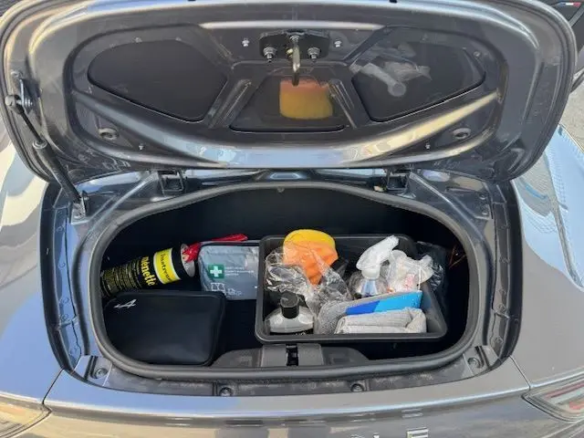 Coffre avant ouvert de l'Alpine A110 1.8T 252 Légende gris acier Heritage, montrant rangement avec trousse de secours et accessoires.