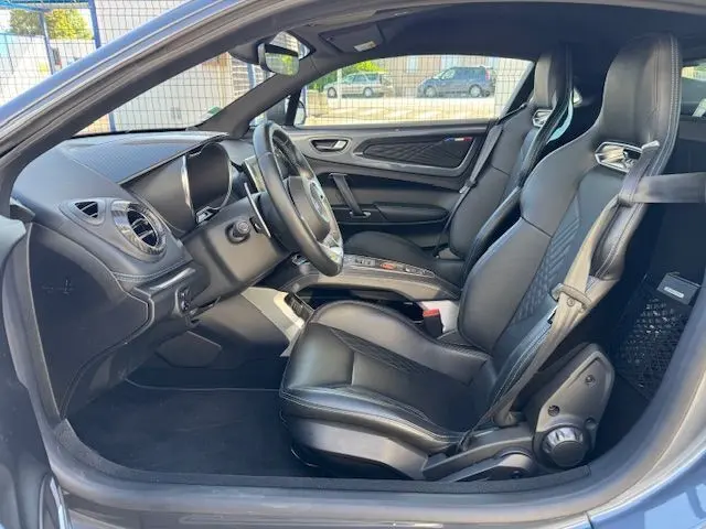 Intérieur côté conducteur de l'Alpine A110 1.8T 252 Légende 2021 avec sièges sport cuir noir et tableau de bord moderne.