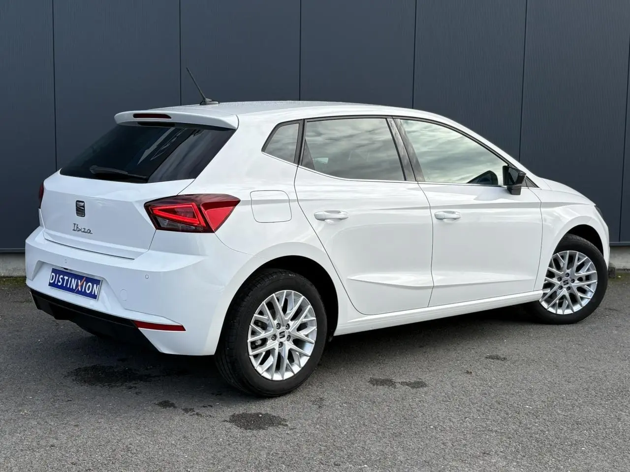 Vue 3/4 arrière droite d'une SEAT Ibiza blanche avec jantes alliage et vitres arrière surteintées.