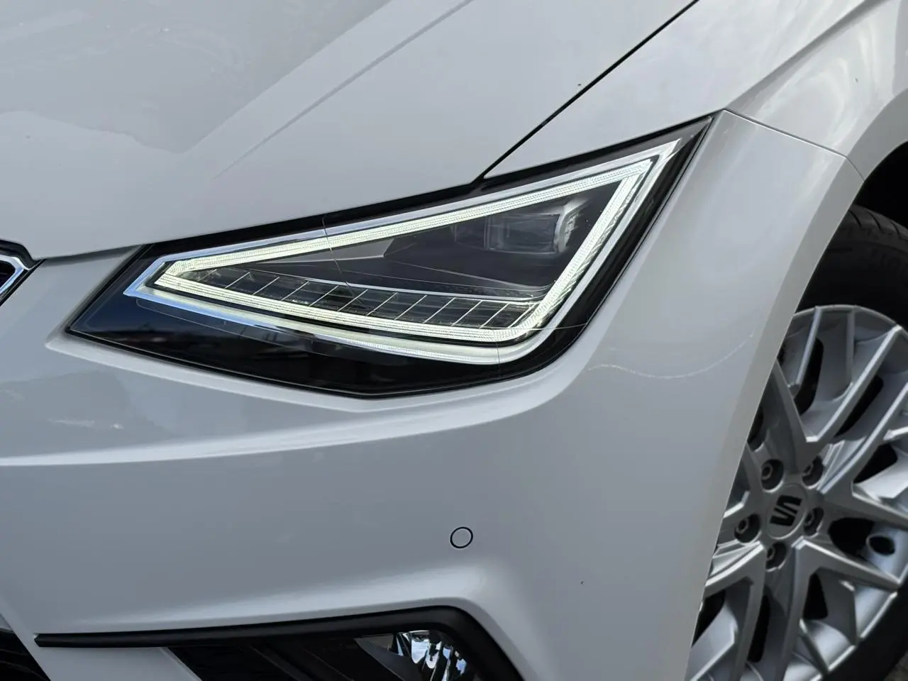 Gros plan sur le phare avant droit et la jante alliage 16 pouces d'une SEAT Ibiza blanche 2025 finition Xcellence.