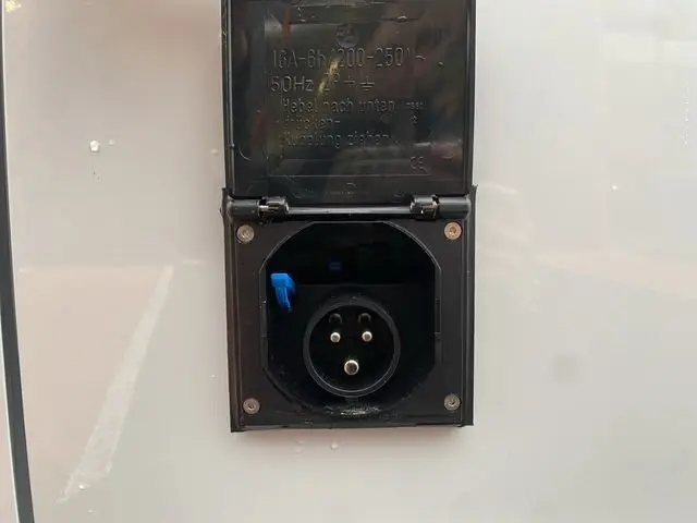 Prise électrique noire encastrée sur la carrosserie blanche du Citroën Jumpy XL 2.0 BlueHDi 2025, vue en gros plan.