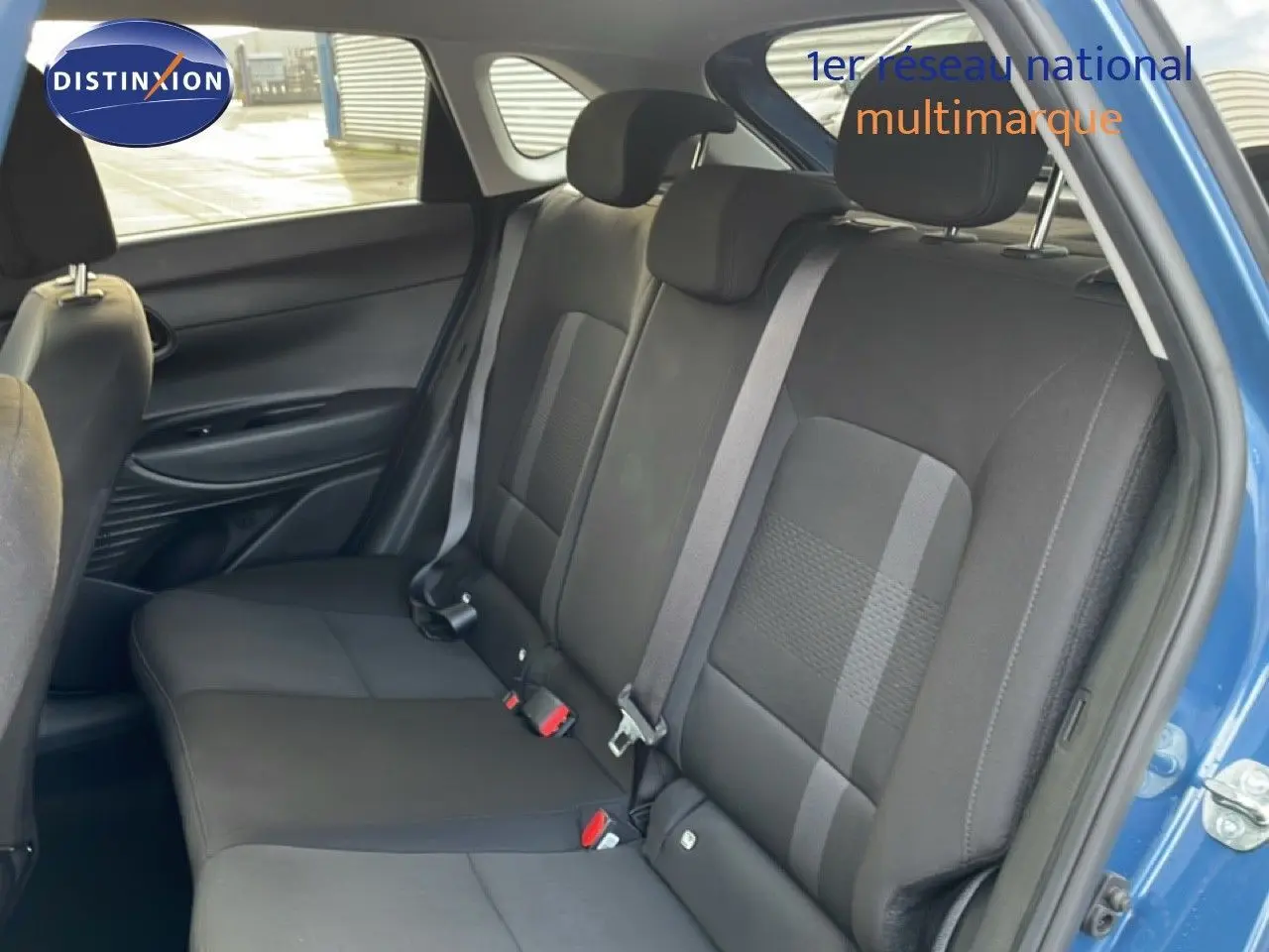 Vue intérieure montrant la banquette arrière noire de la Hyundai i20 2025, porte arrière droite ouverte bleu vibrant métal.