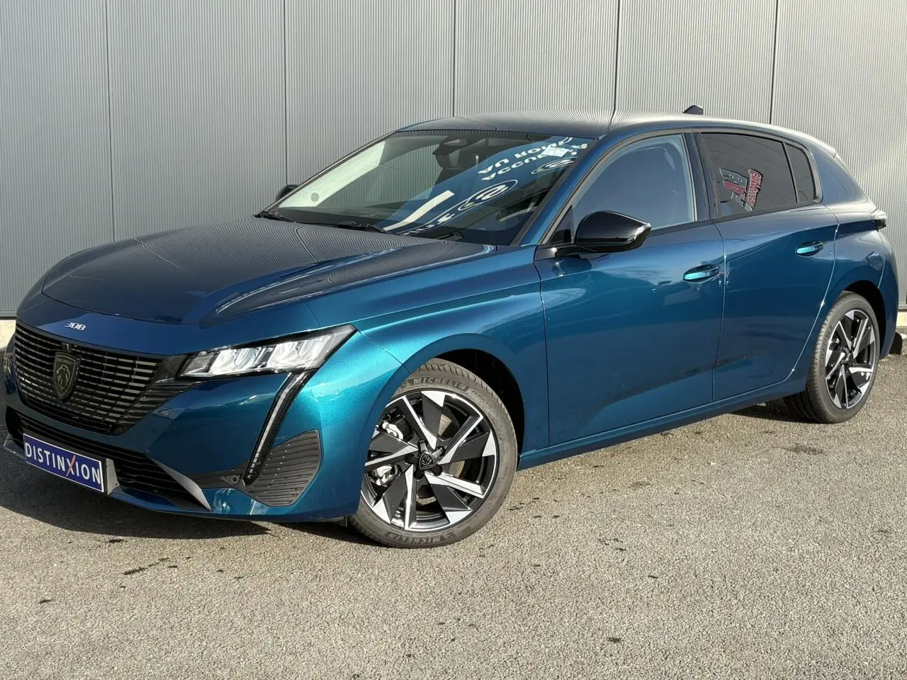 Peugeot 308 Hybrid 2025 en bleu Obsession, vue 3/4 avant droit avec jantes alliage et calandre noire distinctive.